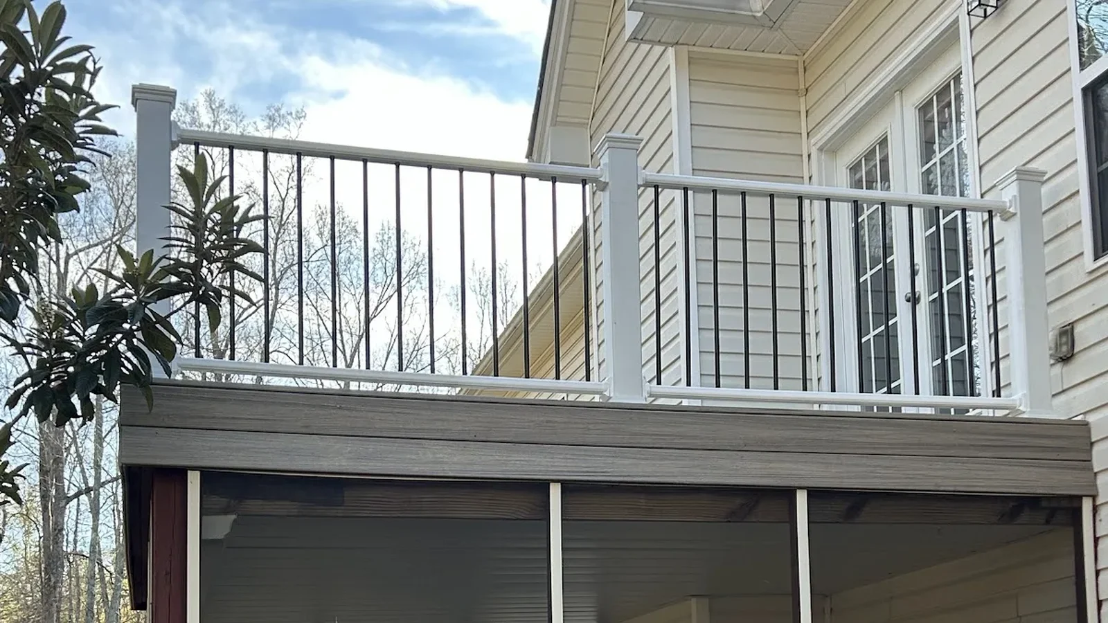 Two story deck with white railing and black balusters above a screened porch, built by The handyman in Griffin, GA